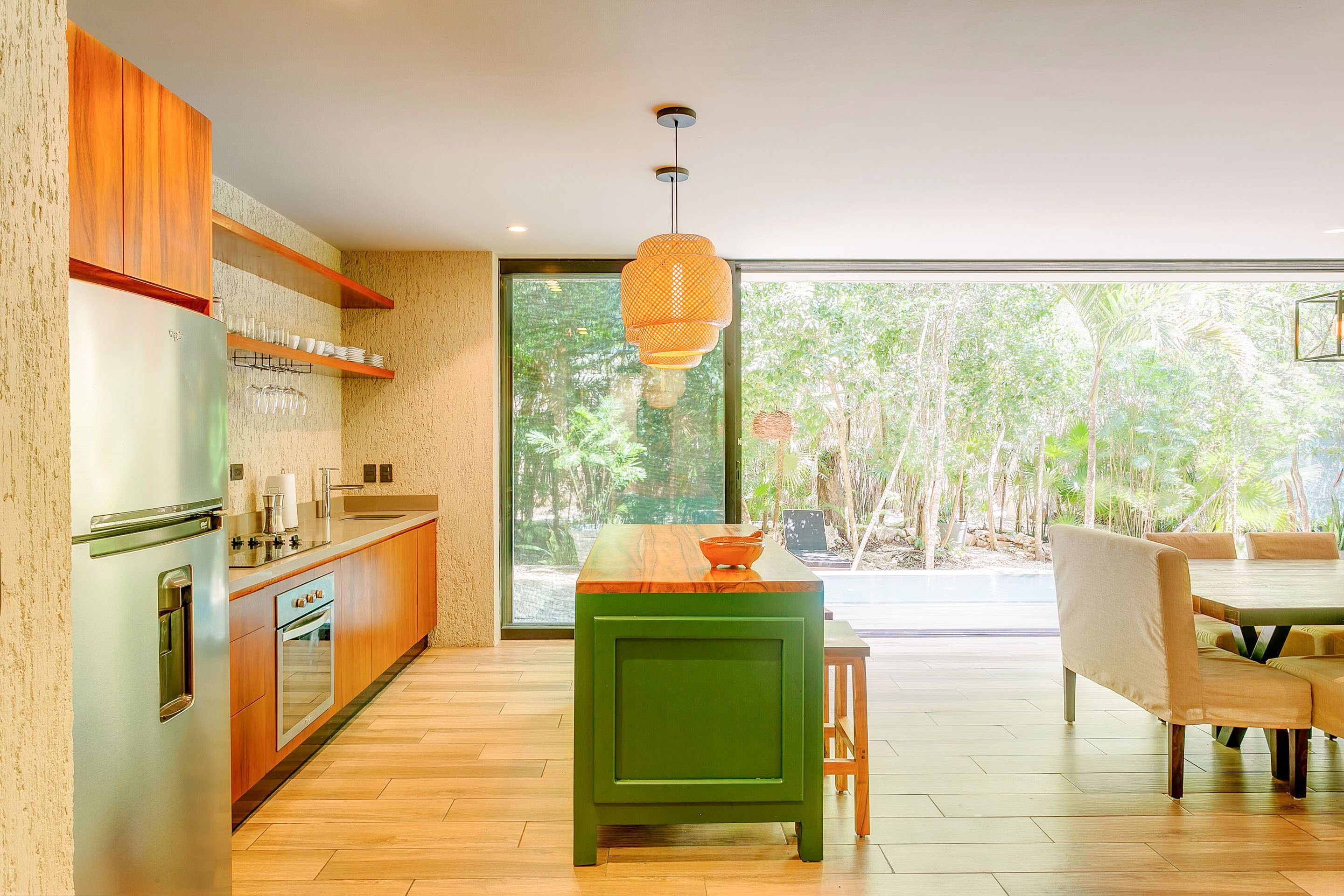 Uma cozinha moderna com geladeira embutida, armários de madeira e uma ilha verde.