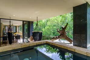 Un espace piscine intérieur moderne offrant une vue dégagée sur la végétation luxuriante environnante.