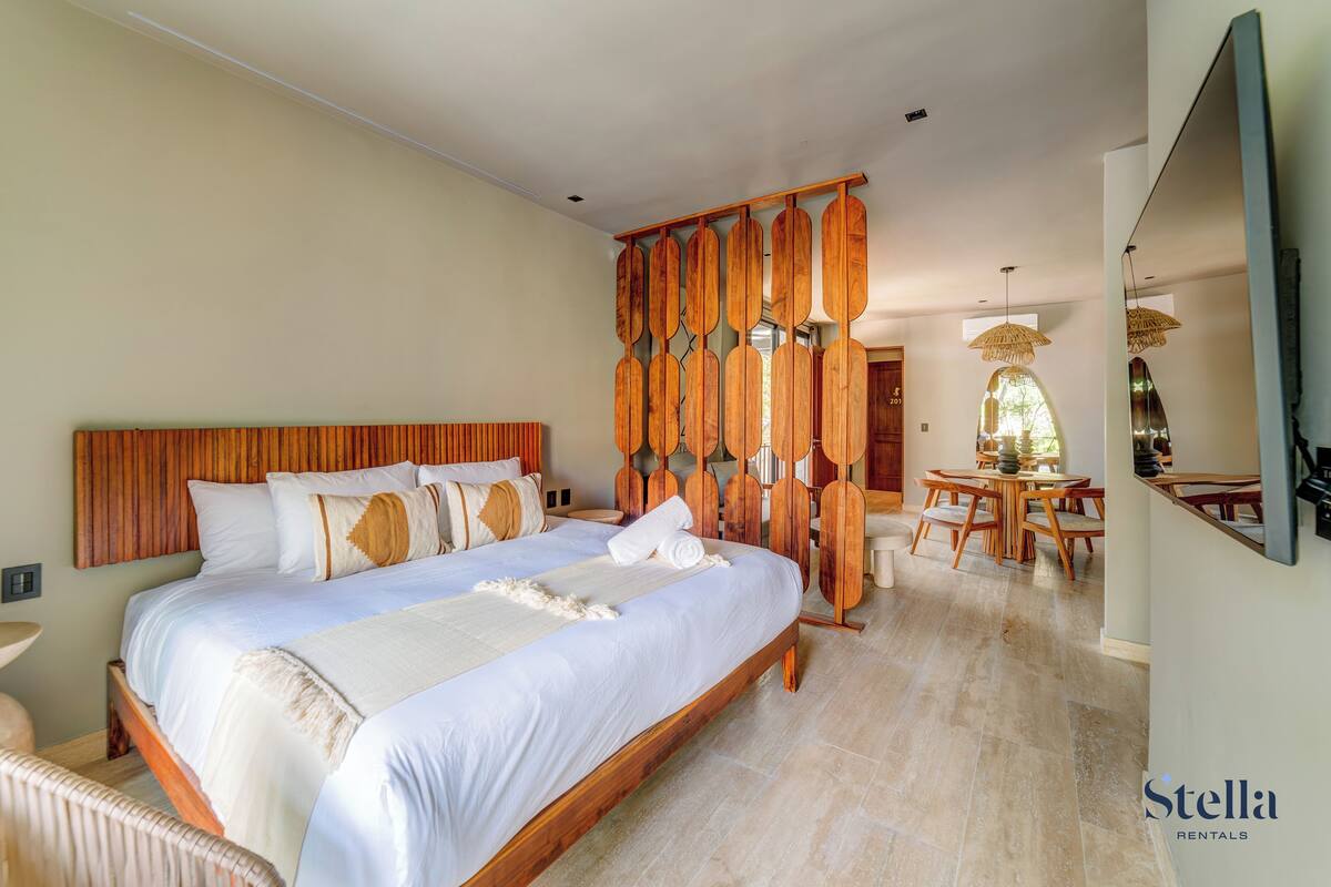 Une chambre spacieuse avec un grand lit, une tête de lit en bois et un panneau décoratif mural.