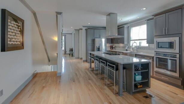A modern kitchen with a central island, stainless steel appliances, and a view to the living area.