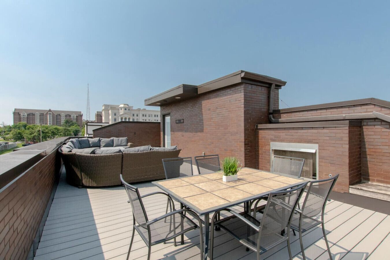 A rooftop terrace with a dining table, chairs, and a sofa.