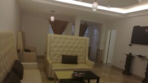 A living room with a beige sofa, a black coffee table, and a large armchair. - Casa Suit Capir (Malabo)