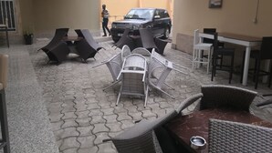 An outdoor seating area with wicker furniture and a car parked nearby. - Casa Suit Capir (Malabo)