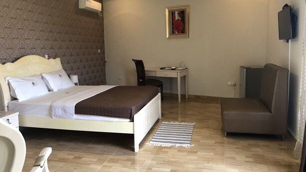 A hotel room with a bed, a desk, a chair, a sofa, and a small table. - Casa Suit Capir (Malabo)
