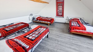 Ein Zimmer mit drei Betten, einem Wandbild mit einer roten Telefonzelle, einer Lampe und einer Decke mit Holzbalken.