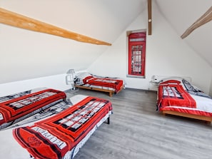 Een kamer met drie bedden, een wanddecoratie met een rode telefooncel, een lamp en een plafond met houten balken.