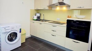 Una cocina compacta equipada con lavadora, cafetera y lavavajillas.