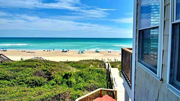 Vista a la playa desde un edificio con balcón que domina el océano.