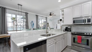 A modern kitchen with white cabinets, a stainless steel dishwasher, a double oven, and a built-in microwave. - 2 Side-by-Side Waterfront Condos • 4BR/4BA • Walk to Beach (Clearwater)