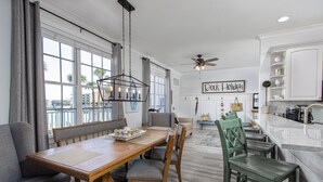 A spacious dining area with a wooden table, chairs, and a view of the city through large windows. - 2 Side-by-Side Waterfront Condos • 4BR/4BA • Walk to Beach (Clearwater)