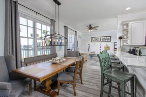 Un vaste espace dédié à la salle à manger, avec une table en bois, des chaises et une vue sur la ville grâce à de grandes fenêtres.