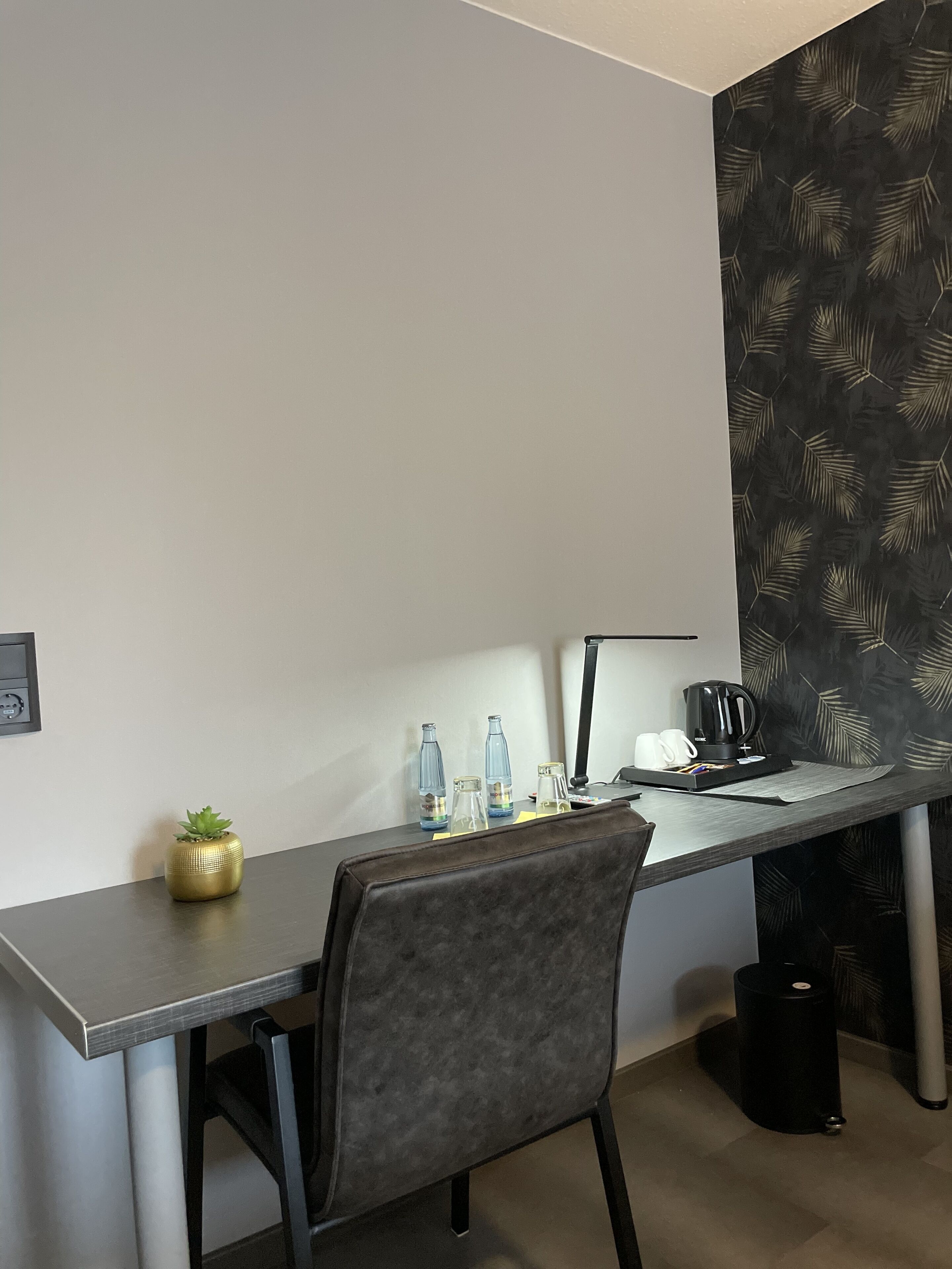 Un espacio de oficina moderno con un escritorio, una silla, una cafetera y objetos decorativos.