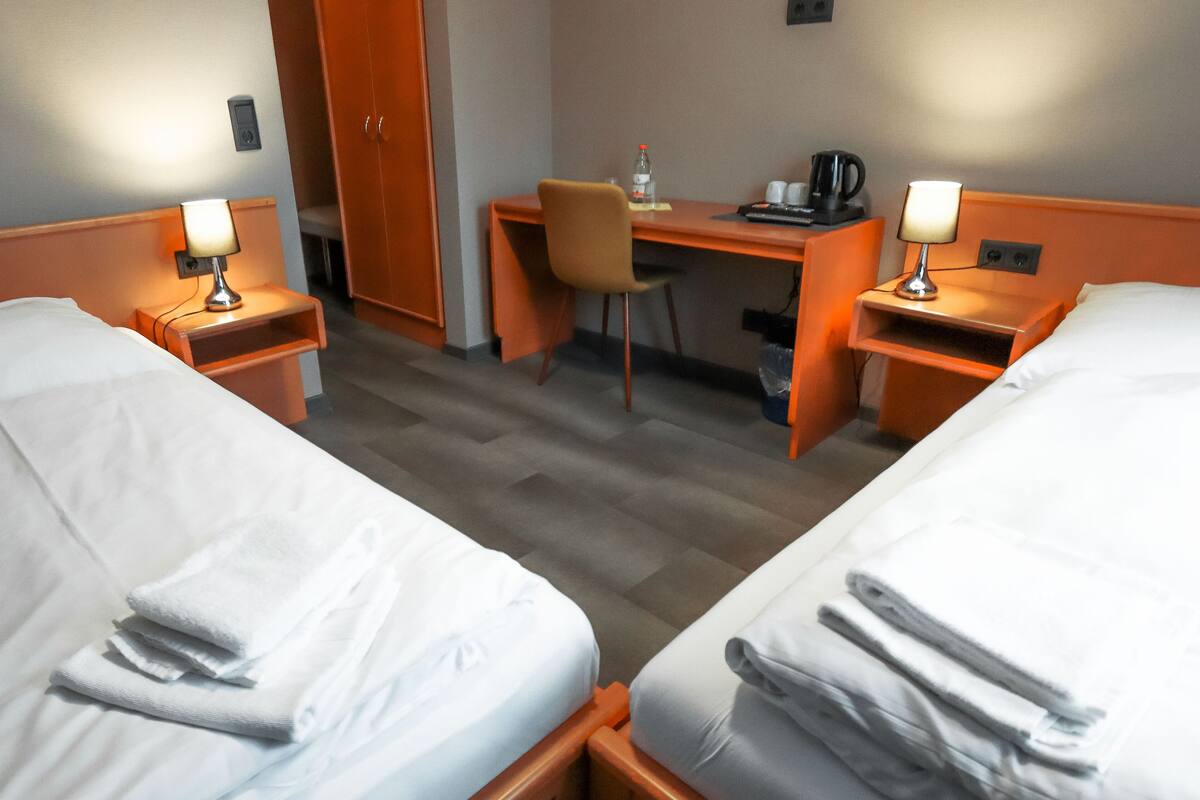 A hotel room with two beds, a desk, a chair, and a coffee maker.