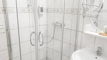 A modern bathroom with a glass-enclosed shower, a white sink, and a mirror.