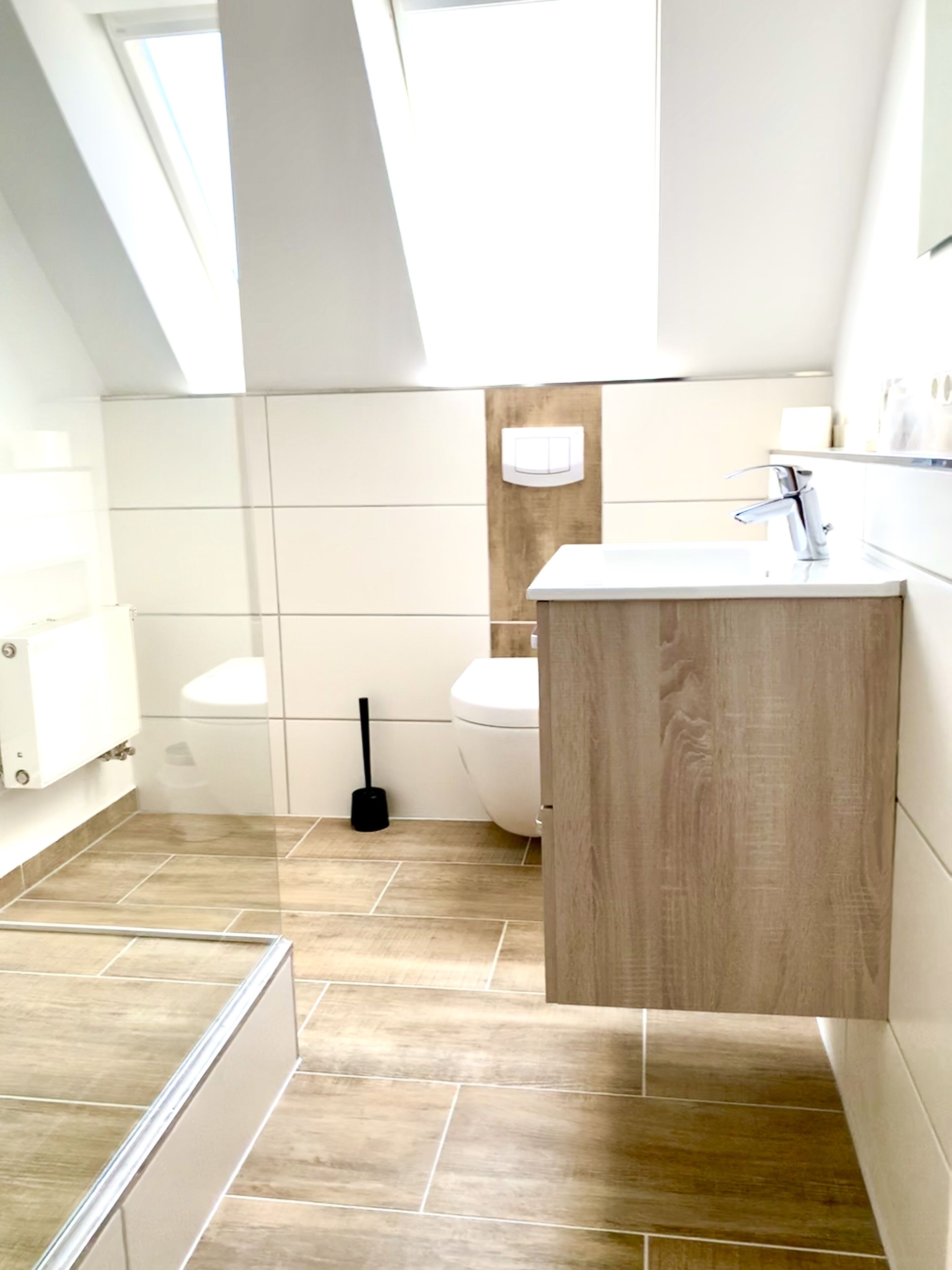 Un baño moderno con tragaluz, tocador de madera, inodoro y zona de ducha.