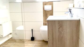 Un baño moderno con tragaluz, tocador de madera, inodoro y zona de ducha.