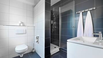 A modern bathroom with a toilet, a shower, and a sink.
