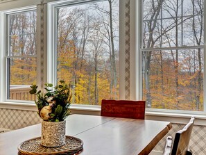A dining area with a table, chairs, and a window with a view of autumn trees. - Golfers dream w/ 5-star experience! Boyne Mountain ski in/out
Garage, fire-pit! (Boyne Falls)