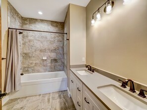 A bathroom with a bathtub, two sinks, a mirror, and a shower curtain. - Golfers dream w/ 5-star experience! Boyne Mountain ski in/out
Garage, fire-pit! (Boyne Falls)