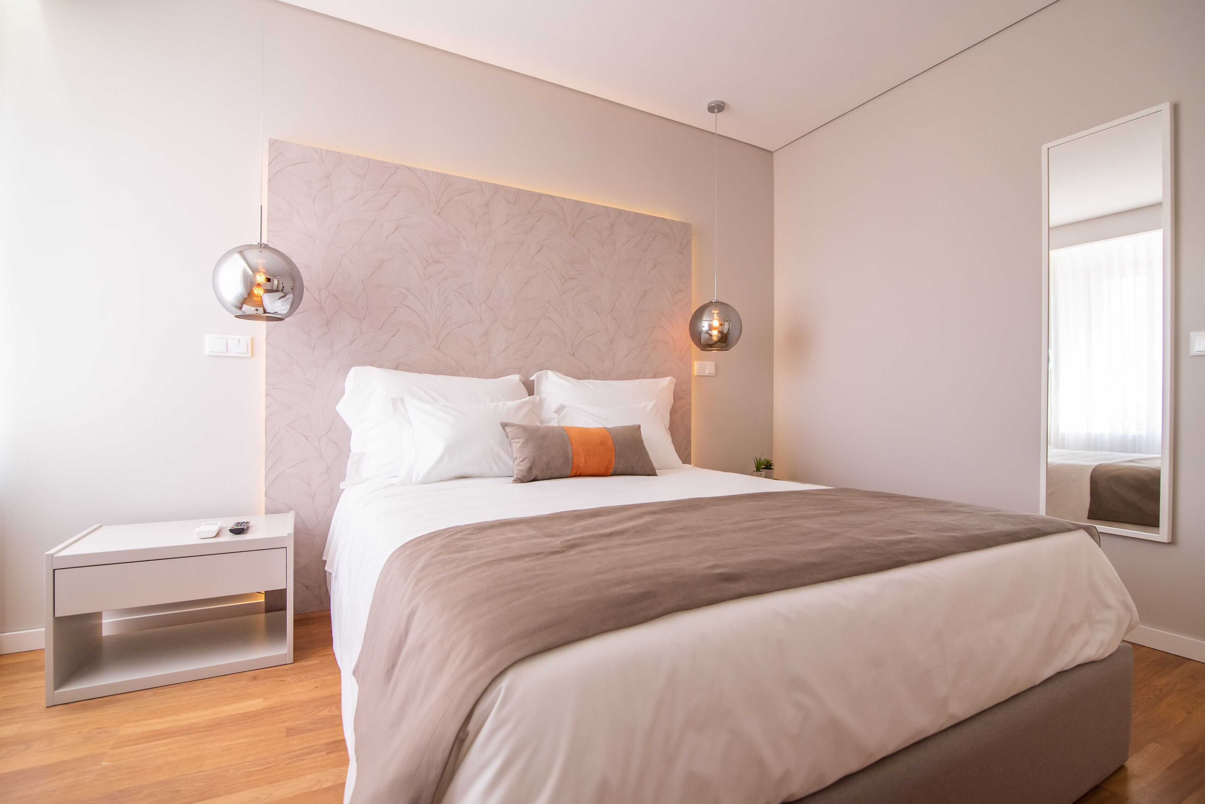 A modern bedroom with a large bed, bedside tables, and wall-mounted lighting.