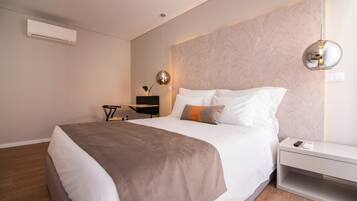 A modern bedroom with a large bed, a bedside table, a wall-mounted air conditioner, and a pendant light.