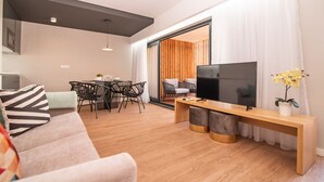 A modern living room with a sofa, TV, wooden console, and dining area. - Villa Esmeralda (Ponta Delgada)