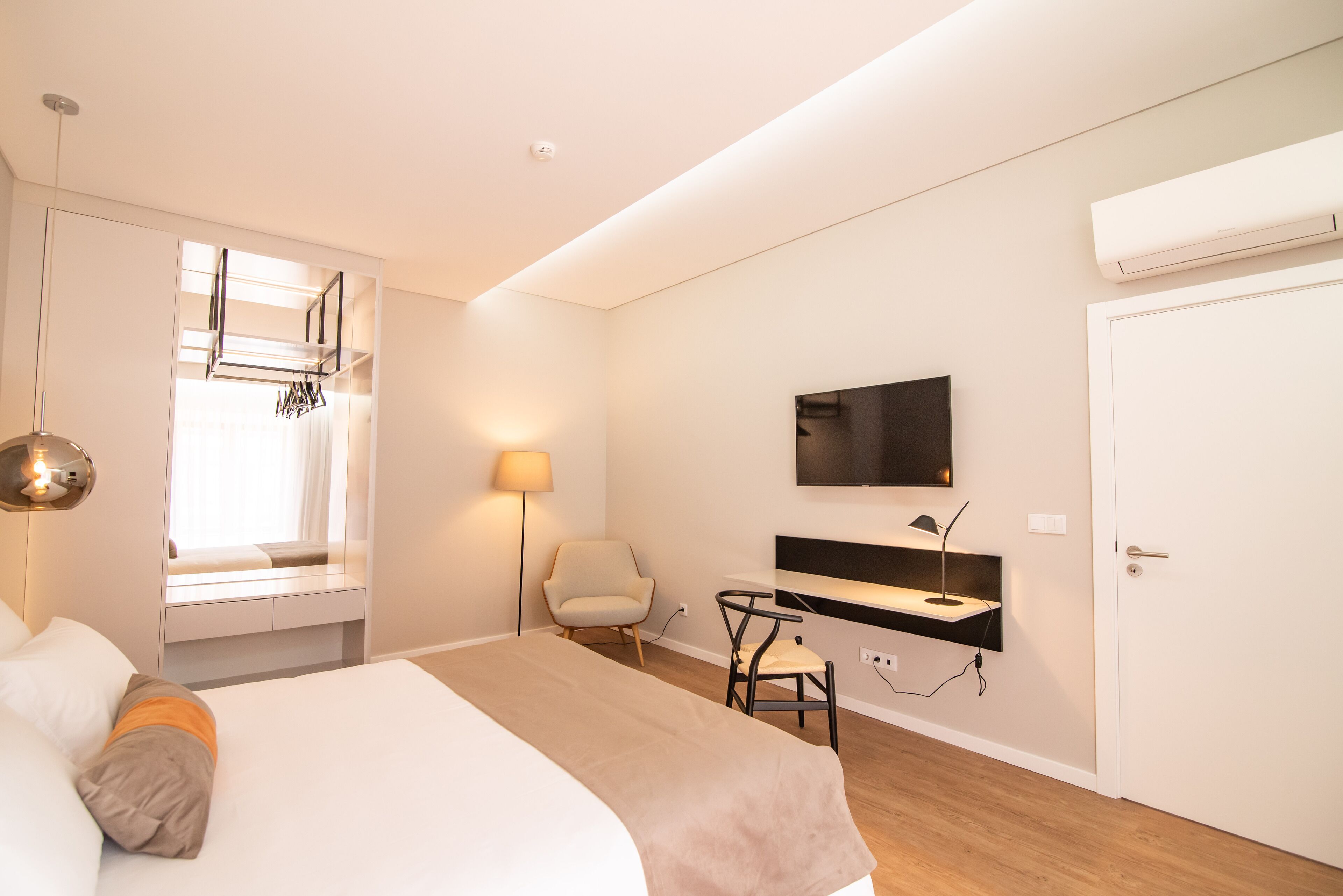Et moderne hotelværelse med seng, skrivebord, stol, fjernsyn og klimaanlæg.