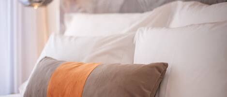 A bed with white and brown pillows, a grey headboard, and a wall-mounted light fixture.