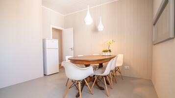 A dining area with a round wooden table, white chairs, and pendant lights.