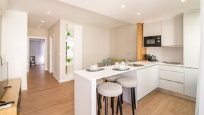 A modern kitchen with a central island, bar stools, and a microwave. - Villa Esmeralda (Ponta Delgada)