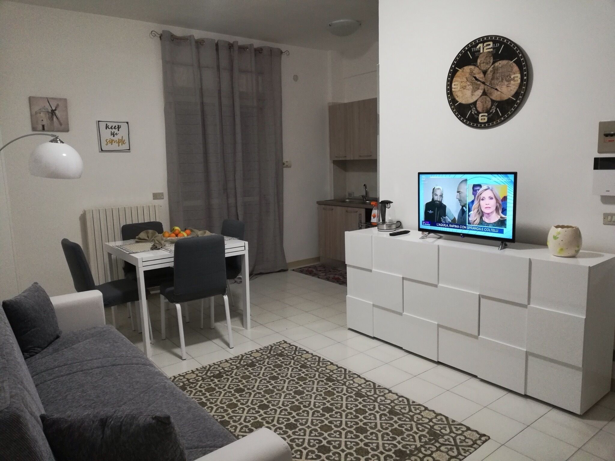 Un menjador modern amb zona de dinar, televisió i cuina al fons.