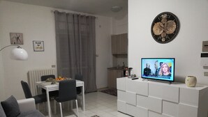 A modern living room with a dining area, a TV, and a kitchen in the background. - Madrigio ... at home (Casamassima)