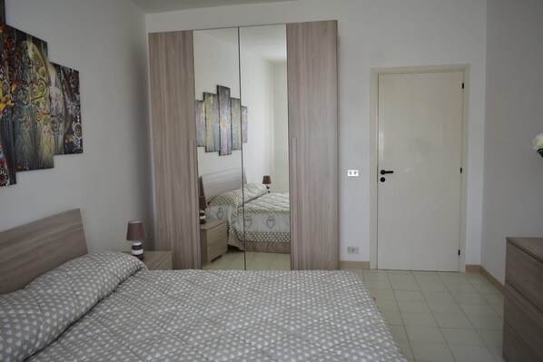 A bedroom with a bed, bedside tables, a wardrobe, and a door.