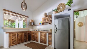 Een moderne keuken met houten kastjes, een roestvrijstalen koelkast en een groot raam met uitzicht op groen.