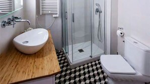 A bathroom with a glass shower enclosure, a white sink, and a toilet. - Apartment, center of Madrid, Embajadores area (Madrid)