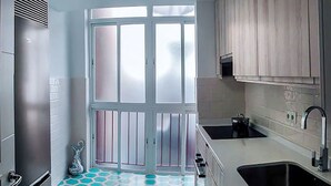 A kitchen with a hexagonal tile floor, a large window, and wooden cabinets. - Apartment, center of Madrid, Embajadores area (Madrid)