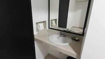 Un baño pequeño con un lavamanos blanco, un espejo y un cubo de basura negro.