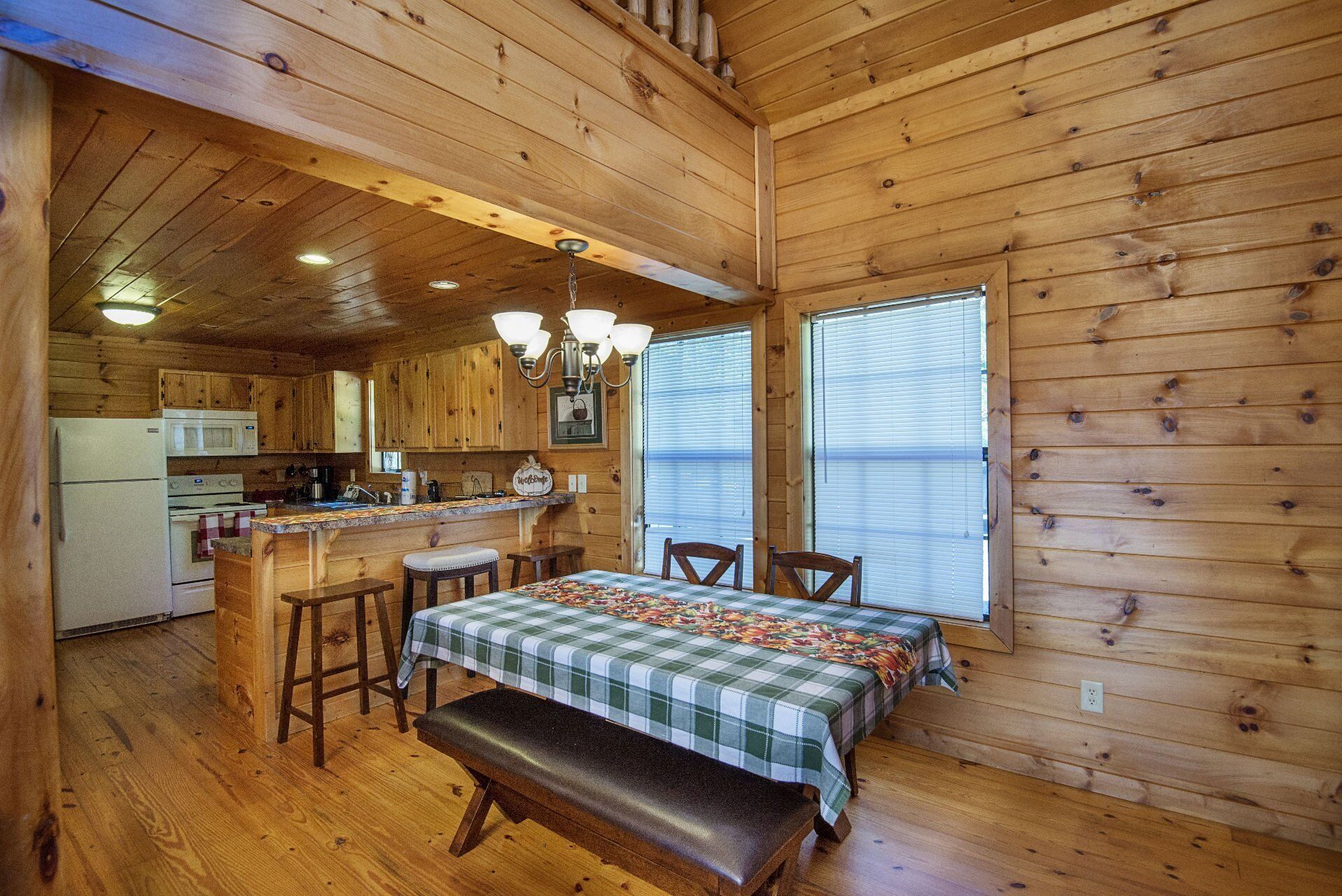A cabin interior with a kitchen, dining area, and a bench.