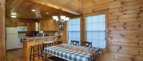 A cabin interior with a kitchen, dining area, and a bench.