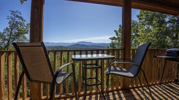 A wooden deck with two chairs and a table, overlooking a mountainous landscape. - Dunder Mountain Views Cabin Retreat (Sevierville)