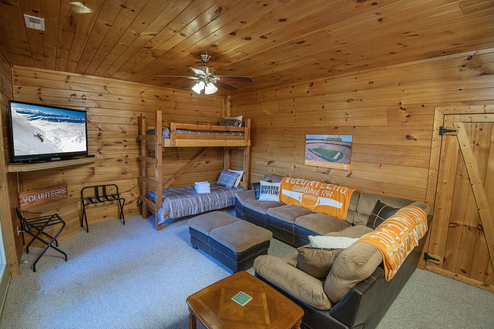 Ein gemütliches Blockhaus mit Etagenbett, einer Couch, einem Fernseher und einem Schild, das auf Freiwilligenarbeit hinweist.