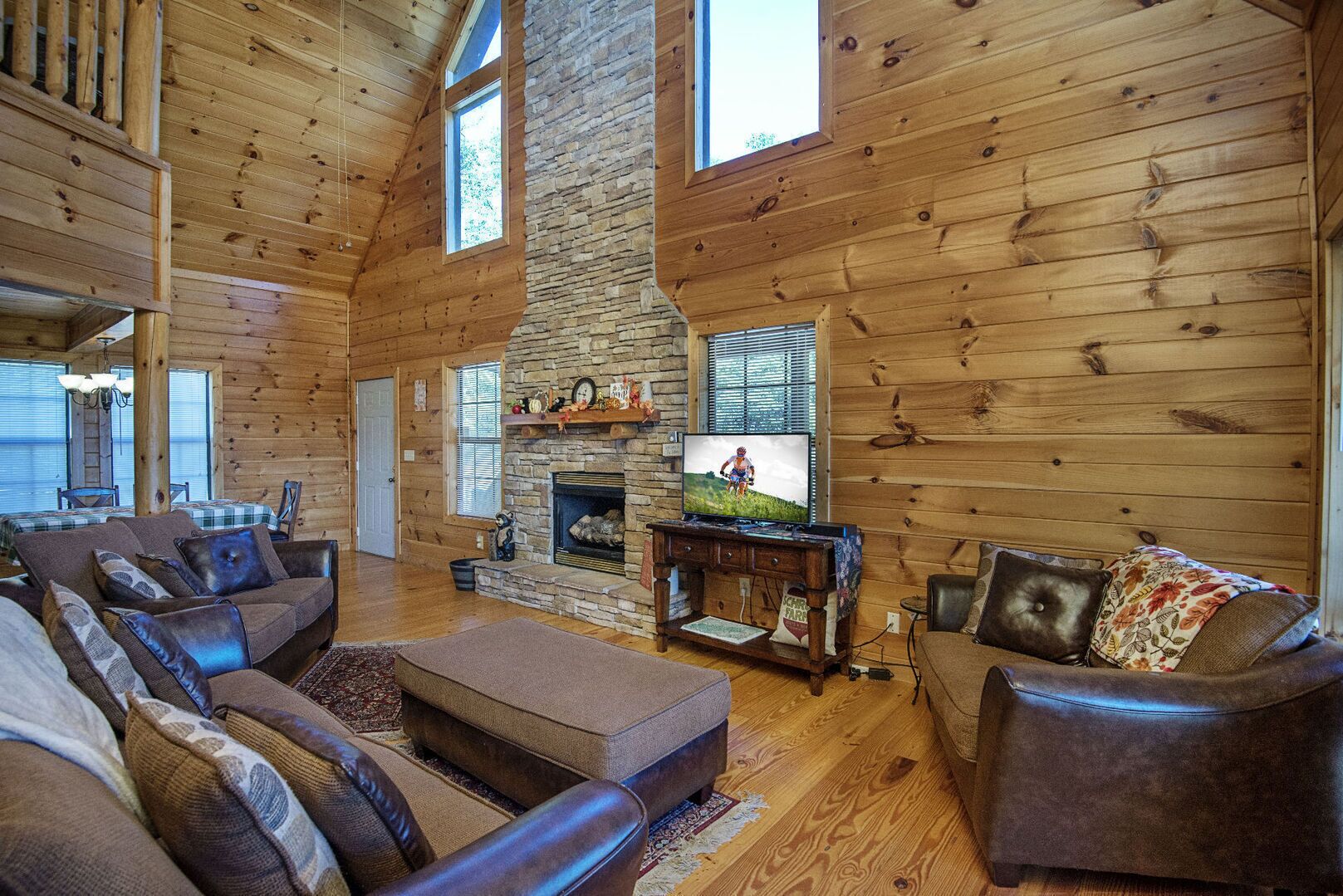 A log cabin interior with a stone fireplace, wooden walls, and a cozy seating area.