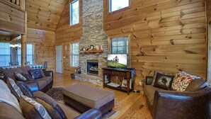 A log cabin interior with a stone fireplace, wooden walls, and a cozy seating area. - Dunder Mountain Views Cabin Retreat (Sevierville)