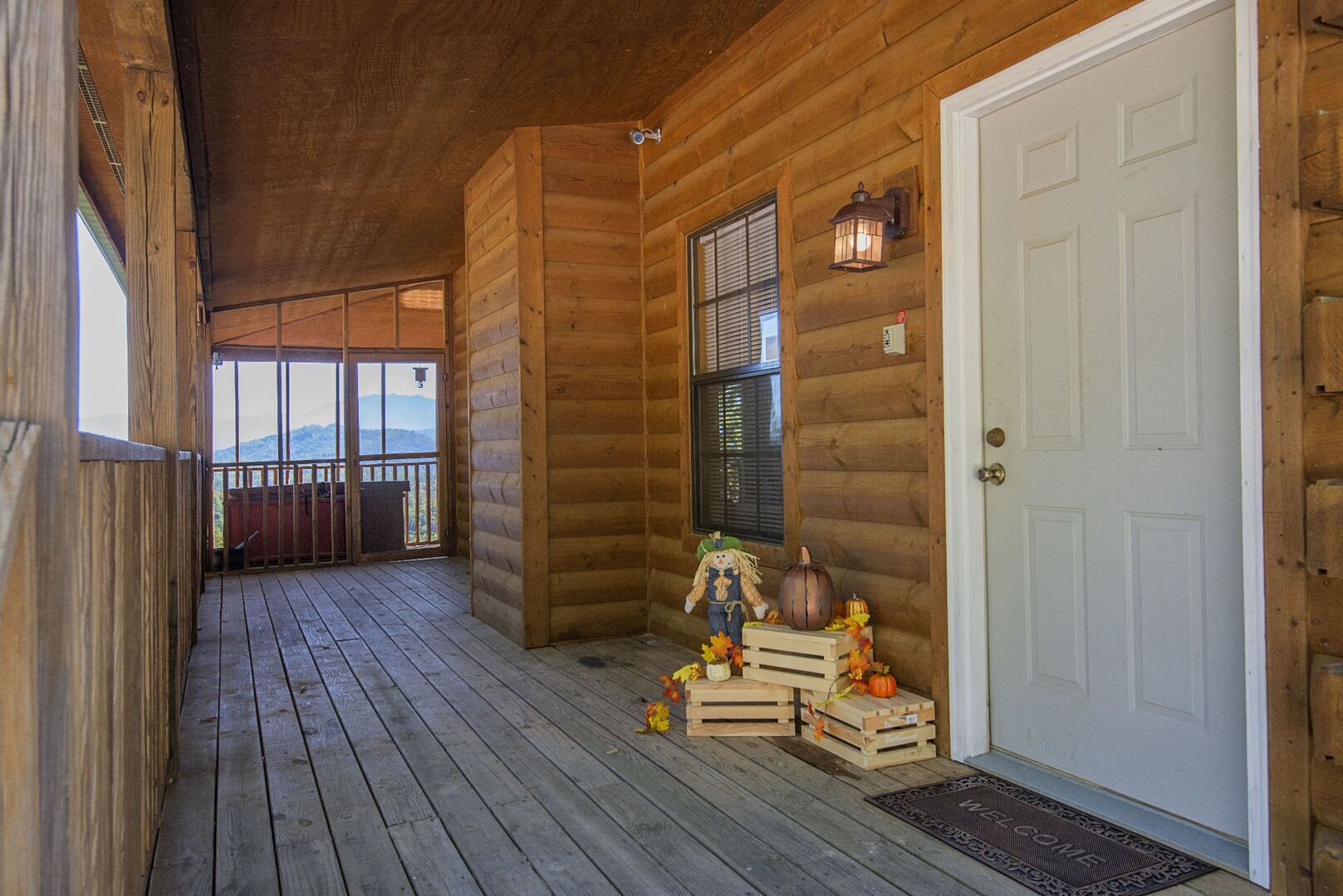 A wooden cabin with a porch, a white door, and a view of mountains.