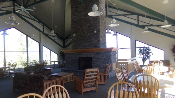 A spacious indoor area with a stone fireplace, wooden furniture, and large windows allowing natural light. - Three House 2 Bed 2 Bath THWC (Silverthorne)