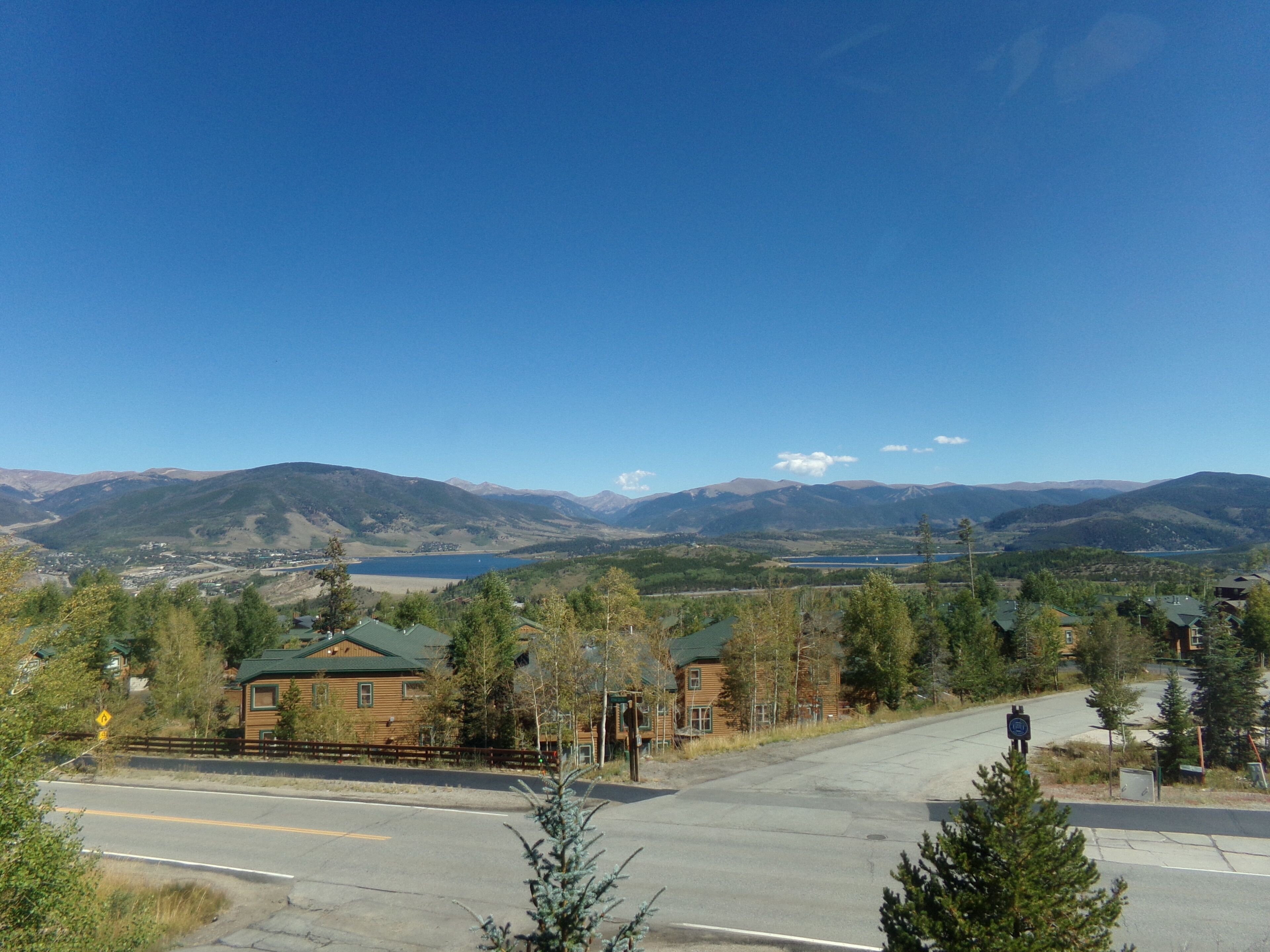 A view of a mountain town with a road leading to a building with a green roof.