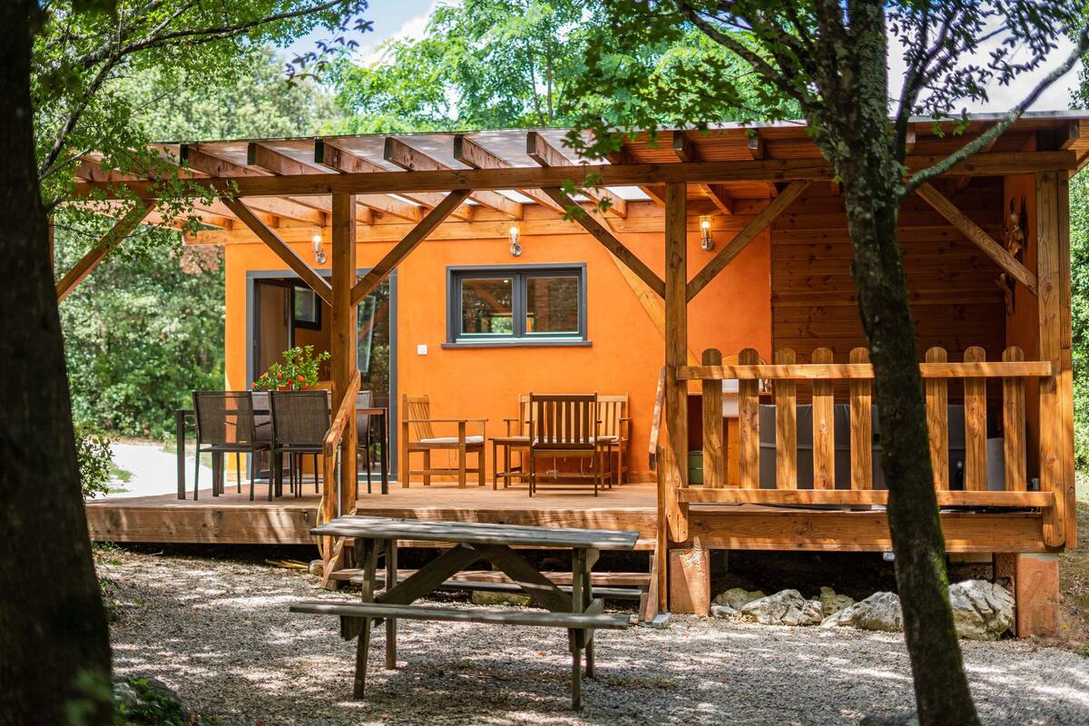 Eine Holzhütte mit Veranda, Sitzgelegenheit im Freien und einem Picknicktisch.