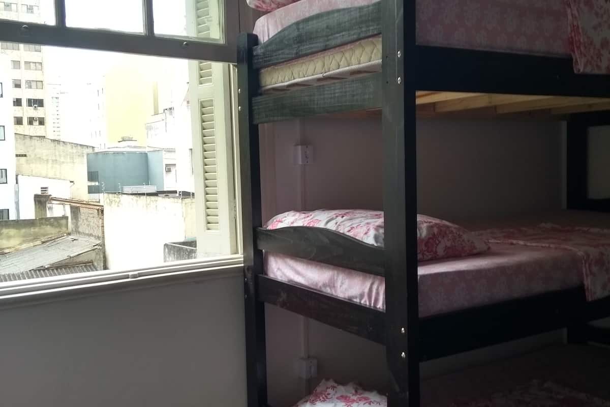 Une chambre avec un lit superposé et une fenêtre donnant sur le paysage urbain.