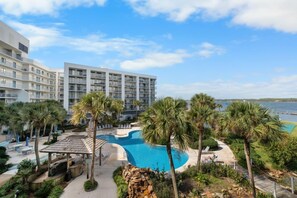 A resort with a swimming pool, palm trees, and a view of the ocean.