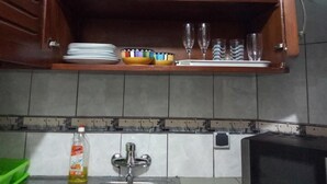 Una cocina con un mueble de madera sobre un salpicadero azulejado, que contiene platos, cuencos y vasos.